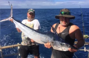 Two fisherman holding a spearfish catch